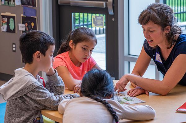 一位老师和三个年轻的学生坐在一张桌子上谈话.